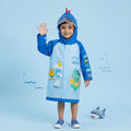 Smiling boy in waterproof blue kids raincoat with dinosaur design