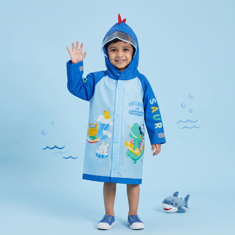 Smiling boy in waterproof blue kids raincoat with dinosaur design
