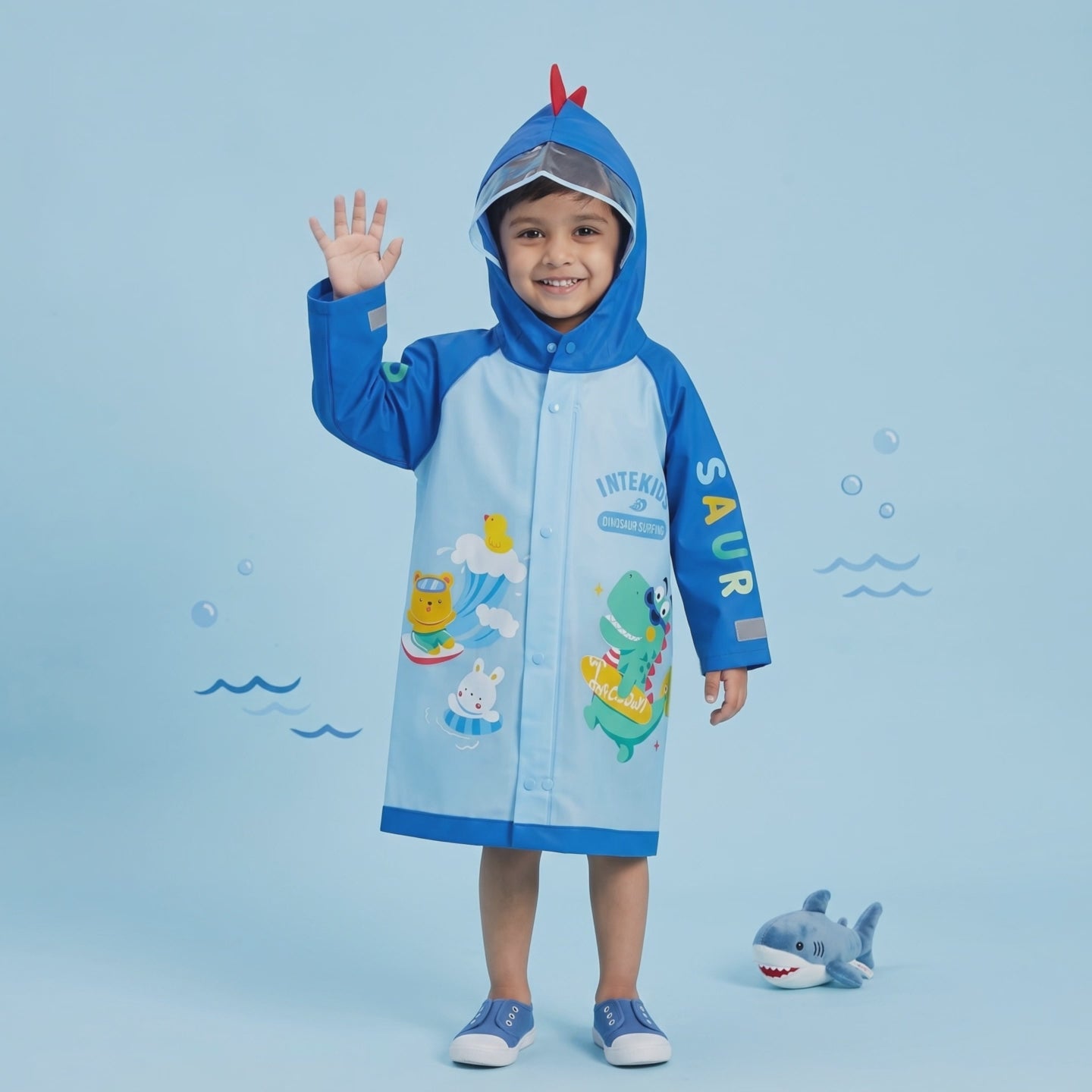 Boy wearing blue kids raincoat with dinosaur hood and print